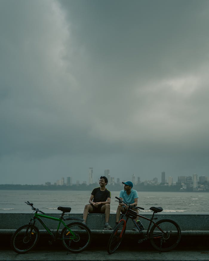 Men with Bikes Sitting on Wall on Sea Shore